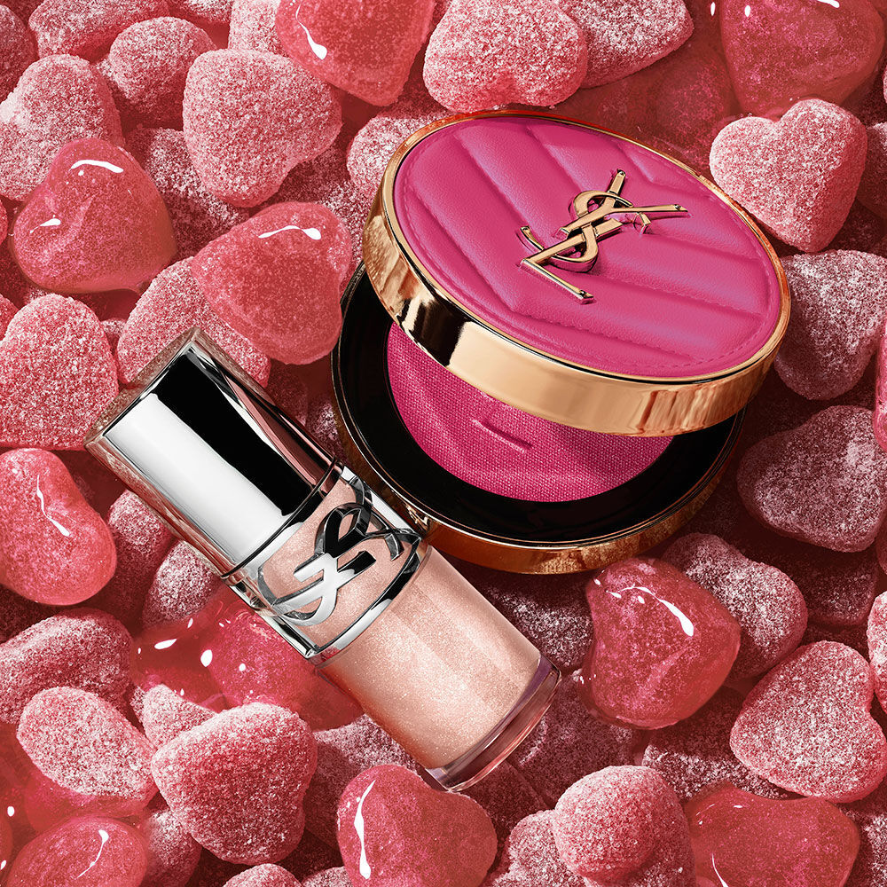 YSL Make Me Blush Powder Blush and LOVESHINE Plumping Lip Oil Gloss in shade 10, nestled among pink heart-shaped candie.