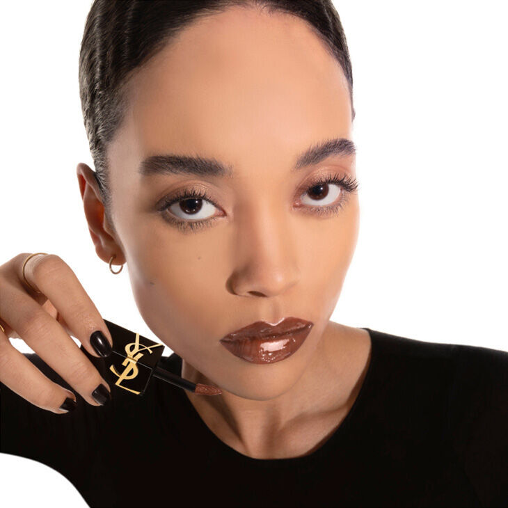Model applying YSL The Inks Vinyl Cream lip stain shade 614 Brown Ignition