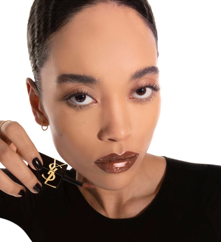 Model applying YSL The Inks Vinyl Cream lip stain shade 614 Brown Ignition