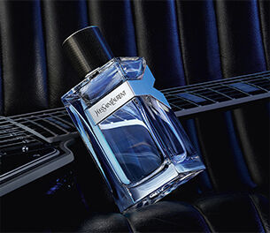 YSL Y Eau de Toilette bottle placed on an electric guitar, showcasing its fresh and energetic fougere fragrance composition.