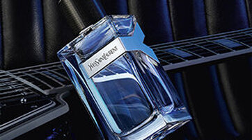 YSL Y Eau de Toilette bottle placed on an electric guitar, showcasing its fresh and energetic fougere fragrance composition.