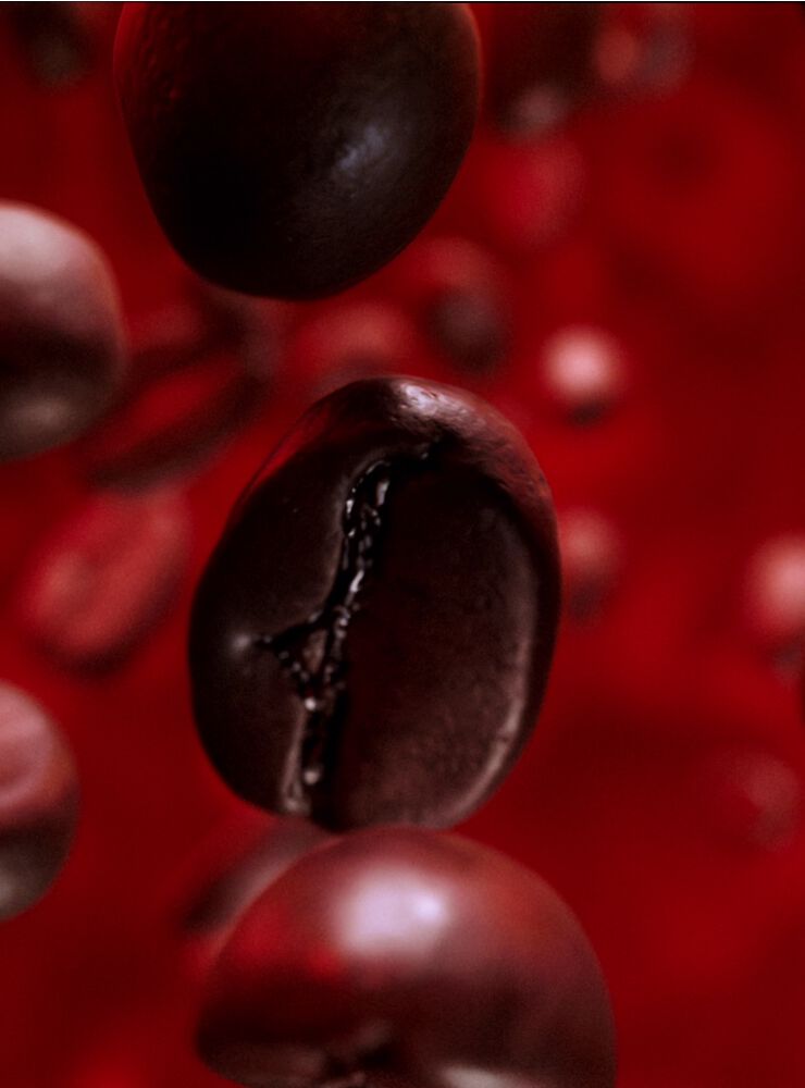 Close-up of coffee beans representing the bold coffee notes in Black Opium Over Red fragrance