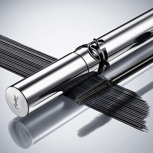 YSL Lash Clash mascara on a reflective surface, showcasing the bold black texture and couture packaging.