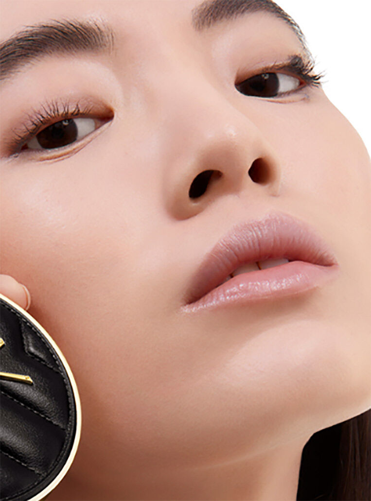 Model holding YSL Le Cushion Encre de Peau cushion emphasizing 24-hour hydration and 78% skincare base