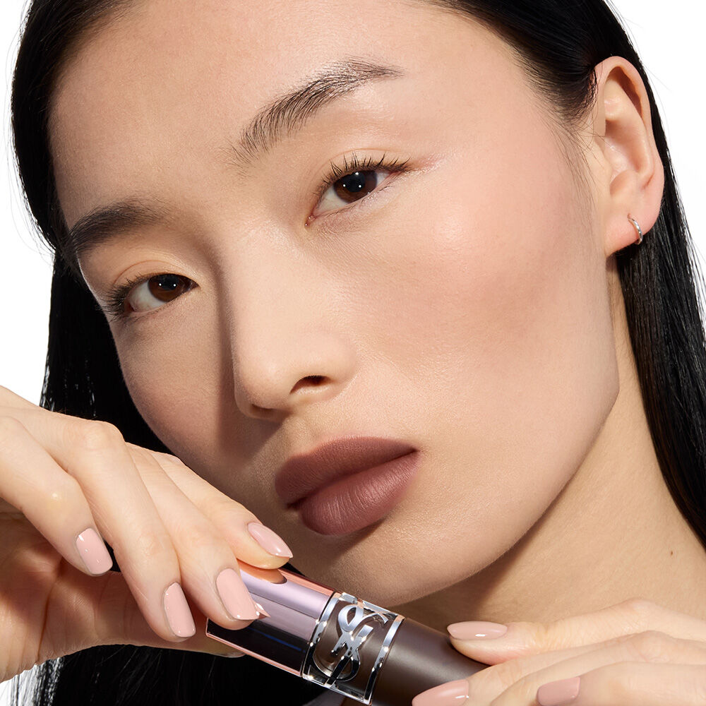 YSL LOVENUDE Kiss Shaper and Lip Blusher in Shade 1, digital still life on a soft pink background.