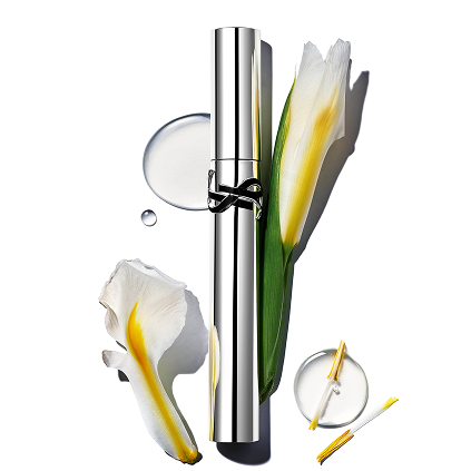 YSL Lash Latex Mascara, a sleek silver tube, elegantly displayed with white and yellow iris flowers and glistening drops of liquid.
