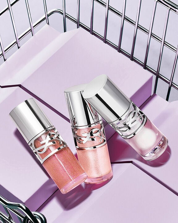 Three YSL Loveshine in shades 10, 11, and 12 displayed on purple blocks in a metallic basket.