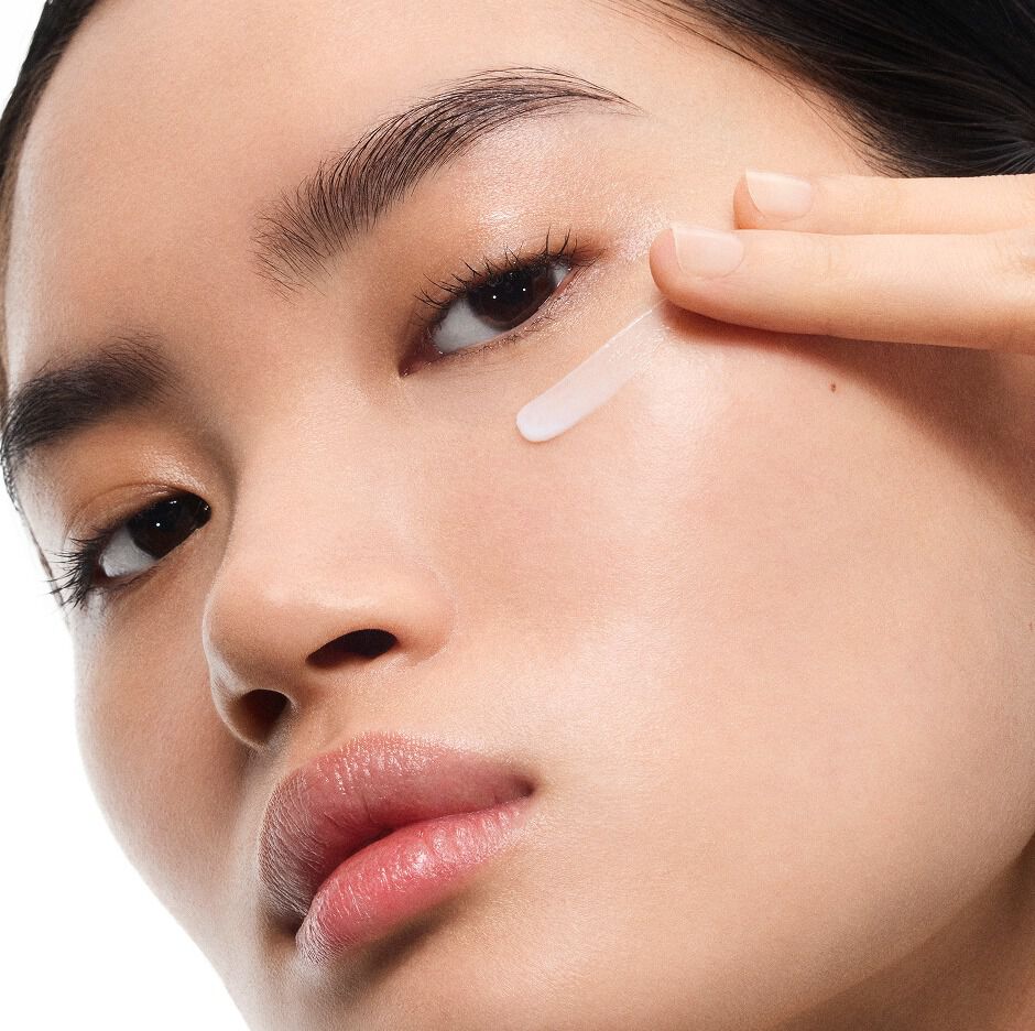 Fair-skinned model Mingma applying YSL Pure Shots Eye Reboot Cream under her eye, showcasing its delicate texture.
