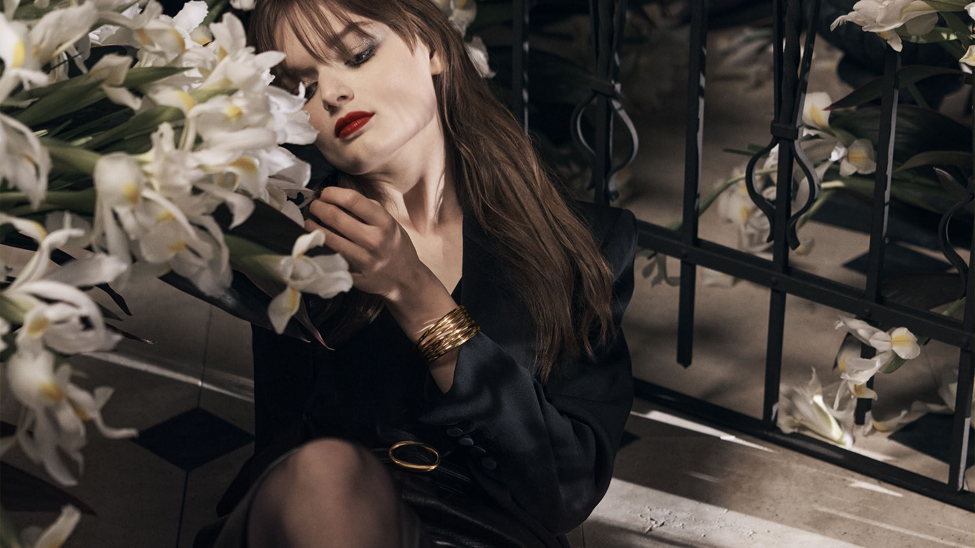 Woman holding white flowers and smelling fragrance in an intimate setting.